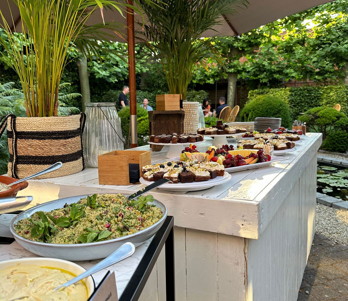 Outdoor buffet table with salads, desserts, and fruit plates