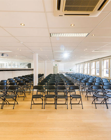 large conference hall with dozens rows of dark chairs