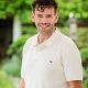 white man with dark hair smiling with white polo shirt