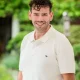 white man with dark hair smiling with white polo shirt