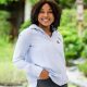 dark woman with blue shirt one hand in trouser pocket