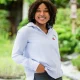 dark woman with blue shirt one hand in trouser pocket