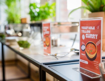 Buffet table with vegan curry sign and serving utensils
